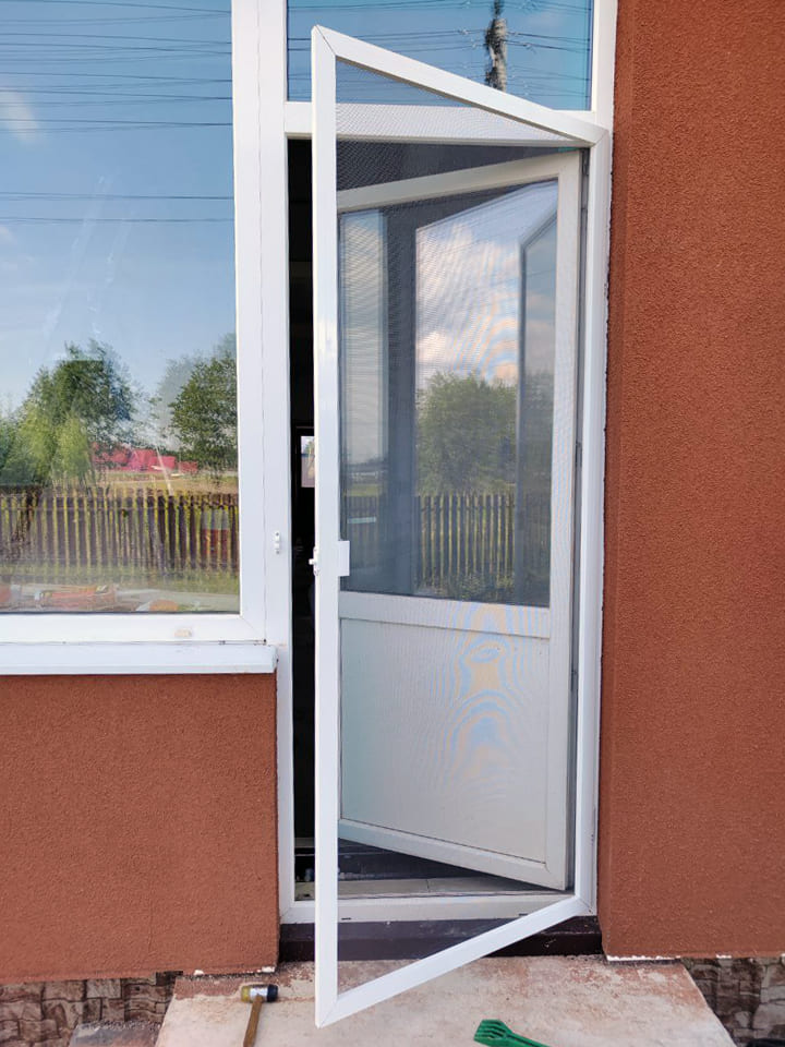 Дверь с установленной дверной москитной сетки. Сетка приоткрыта